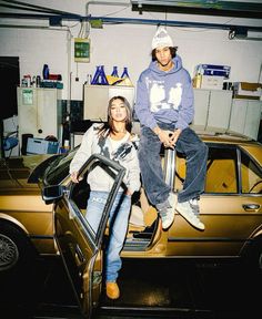 two people sitting on top of a car in a garage