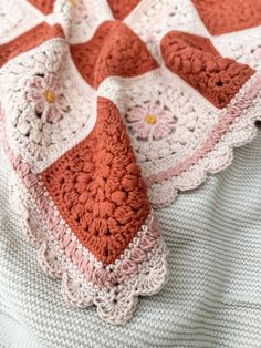 a crocheted blanket is laying on top of a bed