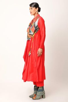 Red angarkha with asymmetric draped panels, landscape pattern yoke, overlap pointed hem panels, multi color patch, zari and thread embroidery. Paired with straight fit pant.
Components: 2
Pattern: Embroidered and Printed
Type Of Work: Applique, Thread and Zari Work
Neckline: Lapel Collar
Sleeve Type: Full Sleeves
Fabric: Silk Chanderi, Cotton Slub
Color: Red
Other Details: 
Fringe drop tassels
Side elasticated waist
Back inverted pleated detail
Length:
Angarkha: 50 inches
Pant: 35 inches
Angarkh Long Unstitched Red Kurta, Red Long Designer Wear Kurta, Red Silk Anarkali Set With Long Sleeves, Red Long Sets For Festivals, Red Salwar Kameez With Sheer Dupatta And Long Sleeves, Red Long Sleeve Salwar Kameez With Sheer Dupatta, Red Anarkali Set With Long Style, Red Anarkali Set With Long Shape, Red Long Anarkali Set