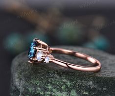 an engagement ring with two blue topaztes and three white diamonds on a rock