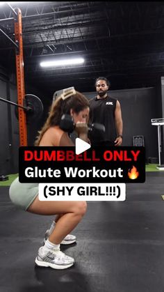 a woman squatting on a gym floor while another man stands behind her in the background