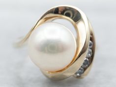 This timeless ring is a gorgeous display of yellow gold and a single saltwater pearl with dazzling diamond accents. The premium quality materials make this piece a valuable addition to any jewelry collection.Metal: 14K Yellow GoldGem: Saltwater PearlGem Measurements: 8.5 mm, RoundAccents: 4 Diamonds totaling .08 Carats, I in Clarity, I-J in ColorRing Size: 4.25Marks: "14K" Stamped on the inside band Yellow Gold Rings With Diamond Accents And Pearl, Yellow Gold Pearl Diamond Ring With Accents, Ring Pearl Modern, Ring Pearl, Gold Pearl Ring, Timeless Ring, Saltwater Pearls, Pearl And Diamond Ring, Ring With Diamond