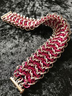 This lovely cuff bracelet is handcrafted, ring by ring, using Elf weave. The cuff comprises of two connected strands of Elf weave chain.  It's made with bright aluminium, in beautiful sparkling silver, and Rad Pink (a dark, hot-pink colour) anodized aluminium rings. The ring size and wire gauge makes it quite chunky.  This cuff bracelet is 2.5cm wide, 0.7cm high and 20.5cm in length, including the plated slide clasp.  Wear it when you're going somewhere special, or as an every day luxury - you d Handmade Silver Friendship Bracelet, Handmade Silver Bracelet For Friendship, Handmade Red Metal Bracelets, Handmade Pink Metal Bracelets, Red Adjustable Metal Cuff Bracelet, Adjustable Red Metal Cuff Bracelet, Handmade Pink Metal Bracelet, Metal Jewelry With Jump Ring For Crafting, Metal Bracelets With Jump Ring For Jewelry Making