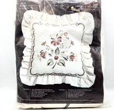 the back of a pillow with flowers on it in a package for sale at a store