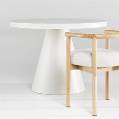 a white table with a wooden chair next to it on a white floored surface