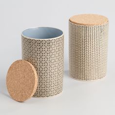 two ceramic containers with cork lids on the sides, one has a circular lid and another has a round bottom