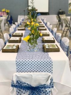 a long table with yellow and blue flowers in vases on top of each table