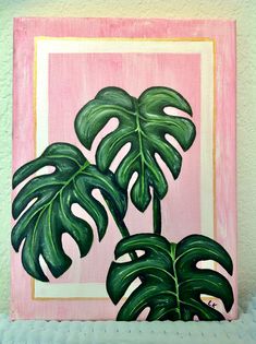 a painting of a green plant in a pink frame