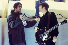 two young men standing next to each other with guitars and microphones in their hands