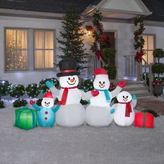 two snowmen are standing in front of a house decorated for christmas with presents on the ground