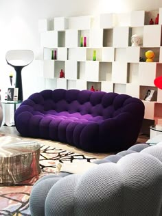 a living room filled with lots of furniture next to a wall mounted shelving unit