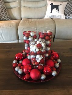 a table topped with two glasses filled with red and silver ornaments next to a couch