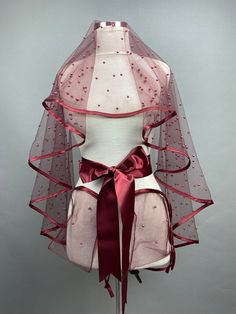 a mannequin wearing a pink veil with red ribbon around the neck and back