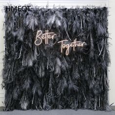 a black feather wall with the words better together written on it and neon lights above