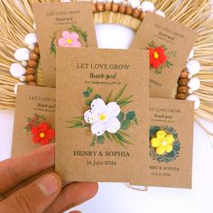 four flower seed packets are held in front of a basket filled with grass and flowers