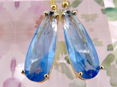 These pale blue teardrop earrings are simply GORGEOUS. These are the earrings you'll want to wear out on that special night when you want to stop traffic! The teardrops are made from bevelled glass with subtle textured cracks inside for added drama, and they're cozied up in beautiful 18k gold-plated copper settings. (Yes! The cracks are there on purpose! They're hung on nickel-free hypoallergenic goldtone iron ear wires, and they come with rubber ear nuts to keep them in place - because you'll b Blue Cubic Zirconia Teardrop Earrings, Blue Teardrop Crystal Earrings, Blue Hypoallergenic Glass Earrings, Cleaning Your Ears, Elegant Blue 14k Gold-filled Earrings, Nickel-free Blue Teardrop Crystal Earrings, Heavy Earrings, Beveled Glass, Gold Studs