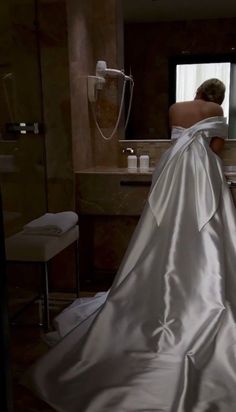 a woman in a wedding dress is looking at herself in the mirror