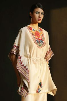 Ivory kaftan-top with multi-color floral motif bead-cord work and tassel tie-up front.
Component: 1
Embroidered
Neckline: Round
Sleeve Length: NA
Fabric: Chanderi
Color: White
Tassel tie-up front
Note: Pant worn by the model is not for sale - Aza Fashions Kaftan Top, Short Kaftan, Embroidered Kimono, Cotton Slip, White Tassel, Embroidered Neckline, Kimono Dress, Designer Wear, Indian Wear