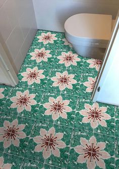 a bathroom with green and white tile flooring next to a toilet in the corner