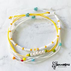 three white and yellow beaded bracelets on a marble surface with the words summer style written below them