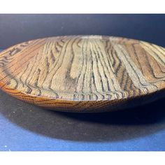 a wooden plate sitting on top of a blue tablecloth covered floor next to a black wall