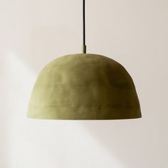 a green lamp hanging from a ceiling in a room with white walls and flooring