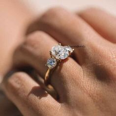 a woman's hand holding an engagement ring with two stones