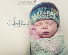 a baby wrapped in a blanket and wearing a knitted hat