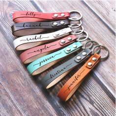 leather keychains with names on them sitting on a wooden table