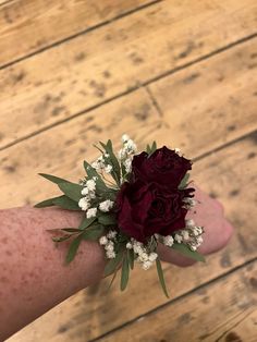 a person's arm with flowers and leaves on it, sitting on a wooden floor