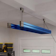 a garage with tools hanging from the ceiling and overhead lighting on the ceiling above it