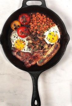 an iron skillet filled with eggs, beans and tomatoes