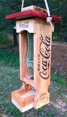 a wooden bird feeder with a coca cola bottle in it