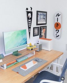 a desk with a computer monitor, keyboard and mouse on it in front of some pictures