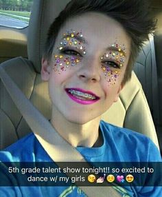 a young boy sitting in the back seat of a car with his face painted like stars