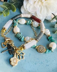 This exquisite bracelet set not only elevates your style but also holds spiritual significance. The Turquoise Chip Beads symbolize tranquility, protection, and healing, fostering a connection to higher realms.  Paired with Pearls and gold-plated accents, it blends elegance with spirituality. The dragonfly, lotus, and flower charms on the gold-filled chain represent transformation, purity, and growth.  The one-inch extender and lobster clasp ensure a perfect fit, making these bracelets a harmonio Bohemian Bracelets With 108 Beads For Jewelry Making, Spiritual Turquoise Beaded Bracelets For Festivals, Bohemian Gemstone Beads Bracelets For Meditation, Bohemian Heishi Beads Bracelets Perfect For Gifts, Bohemian Heishi Beads Bracelets For Gift, Bohemian Heishi Beads Bracelets As Gift, Spiritual Heishi Beads Healing Bracelet, Handmade Spiritual Heishi Beads Jewelry, White Hippie Bracelet Jewelry