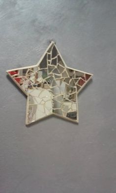 a star shaped mirror with mosaic tiles on the bottom and sides, hanging from a wall