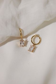 These dainty earrings are made with glass rhinestone charms and 18 karat gold plated huggie hoops. This gold plating protects against wear and tear, tarnishing, and light contact with substances such as water. All earrings are handcrafted with care and custom made to meet your unique needs. Closure options: * Pierced gold hoops are hypoallergenic and nickel free (18 karat gold plated). * Clip on gold hoops are hypoallergenic and nickel free (18 karat gold plated). How to wear clip ons: Hold the earring in one hand while pulling the closure open with the other hand, place the earring onto the thin upper earlobe, then slide the earring down the earlobe to secure in place. Please feel free to message me for any questions! Trendy Hoop Jewelry With Charms, Trendy Hoop Charms Jewelry, Huggie Earrings With Dangling Charms As Gift, Trendy Hoop Earrings With Dangling Charms As Gift, Tarnish Resistant Cubic Zirconia Hoop Earrings As Gift, Gift Cubic Zirconia Tarnish-resistant Hoop Earrings, Trendy 14k Gold Filled Huggie Earrings As Gift, Trendy 14k Gold Filled Huggie Earrings For Gift, 14k Gold Filled Huggie Jewelry With Dangling Charms