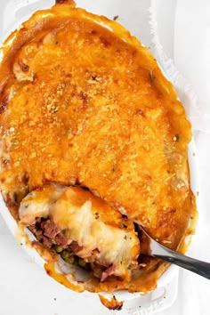 a casserole dish with meat and cheese in it on a white paper plate