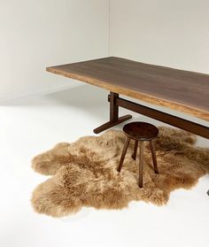 a wooden bench and stool with sheepskin rugs on the floor next to it