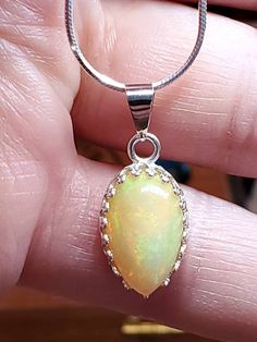 "4.00 carat green, yellow and orange natural Ethiopian opal in a Lacey bezel silver setting on a silver 18 inch chain. 5/8\" x 7/16 is the size of the stone,I will make a chain any length you like." Amber Cabochon Round Pendant Necklace, Amber Cabochon Oval Pendant Necklace, Amber Teardrop Cabochon Necklace, Opal Pendant Necklace With Large Pendant, Amber Cabochon Oval Pendant Jewelry, Amber Oval Necklace With Large Pendant, Handmade Teardrop Opal Jewelry, Amber Sterling Silver Necklace With Cabochon, Amber Cabochon Necklace In Sterling Silver