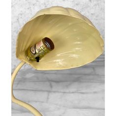 a yellow flower shaped lamp with a bottle in it's center on a marble surface