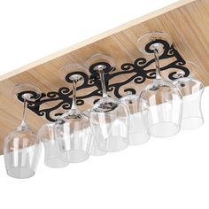 six wine glasses are hanging from the ceiling with an iron scroll design on it's glass holder