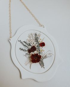 a white plate with flowers on it hanging from a gold chain