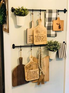 kitchen utensils hanging on the wall with wooden cutting boards and potted plants