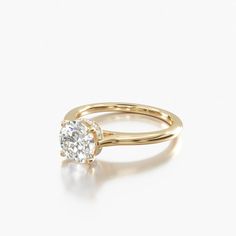 a yellow gold engagement ring with a single diamond in the center, on a white background