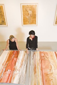 two women are standing in front of an art work on the floor and one woman is looking at it