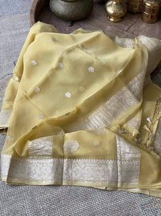 This is a traditional pure banarasi woven georgette saree in beautiful pale yellow colour with an amazing zari weave. Saree features elegantly floriated zari border and pallu. The floral bootis is run throughout the body of the saree. The pallu has paisley bootis in zari weave, the pallu is finished with skill full tassels, which makes it more beautiful. Georgette gives a very beautiful drape owing to its flowy nature. Color: Pale Yellow Length: 5.5 Meters Width: 1.2 Meters Blouse: Running/attac Sheer Dupatta Traditional Wear For Diwali, Organza Cutdana Dupatta For Traditional Ceremonies, Traditional Organza Dupatta With Zari Weaving, Organza Traditional Wear For Festivals, Traditional Organza Saree For Ceremonies, Organza Traditional Wear For Ceremonies And Festivals, Traditional Wear With Zari Weaving And Organza, Traditional Organza Wear For Traditional Ceremonies, Traditional Organza Wear With Self Design