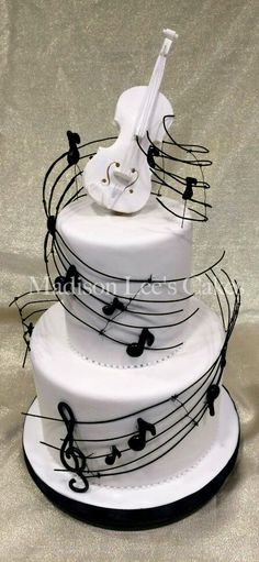 a three tiered cake decorated with musical notes and a white violin on the top