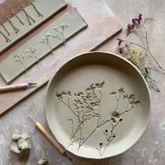 some dried flowers are sitting in a bowl on a table next to tools and paper